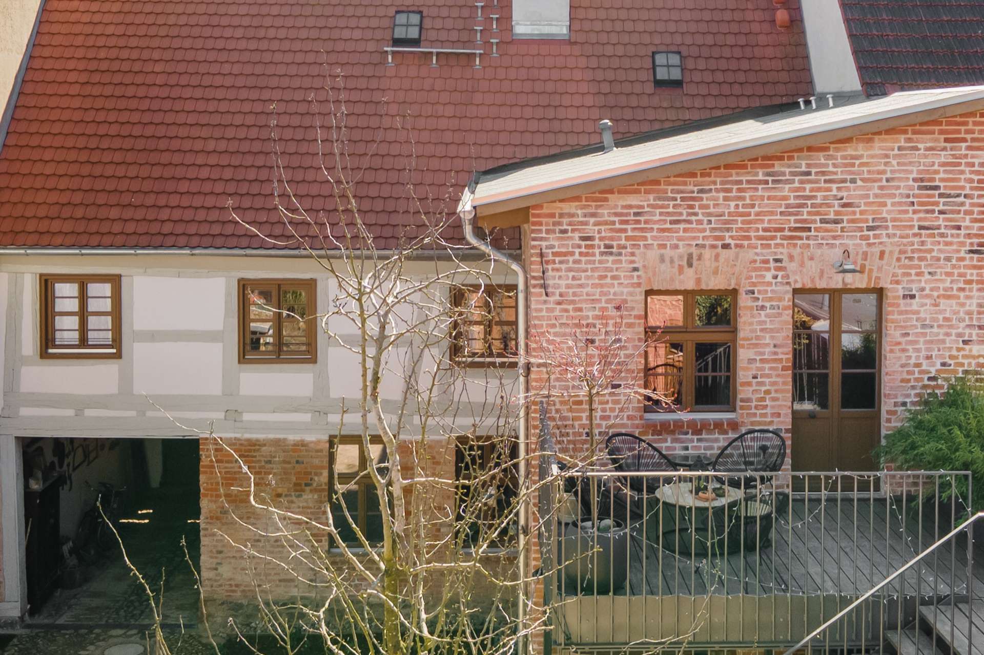 Innenhof und Fachwerkfassade der Alten Tischlerei Gransee mit weitläufiger Holzterrasse im Obergeschoss