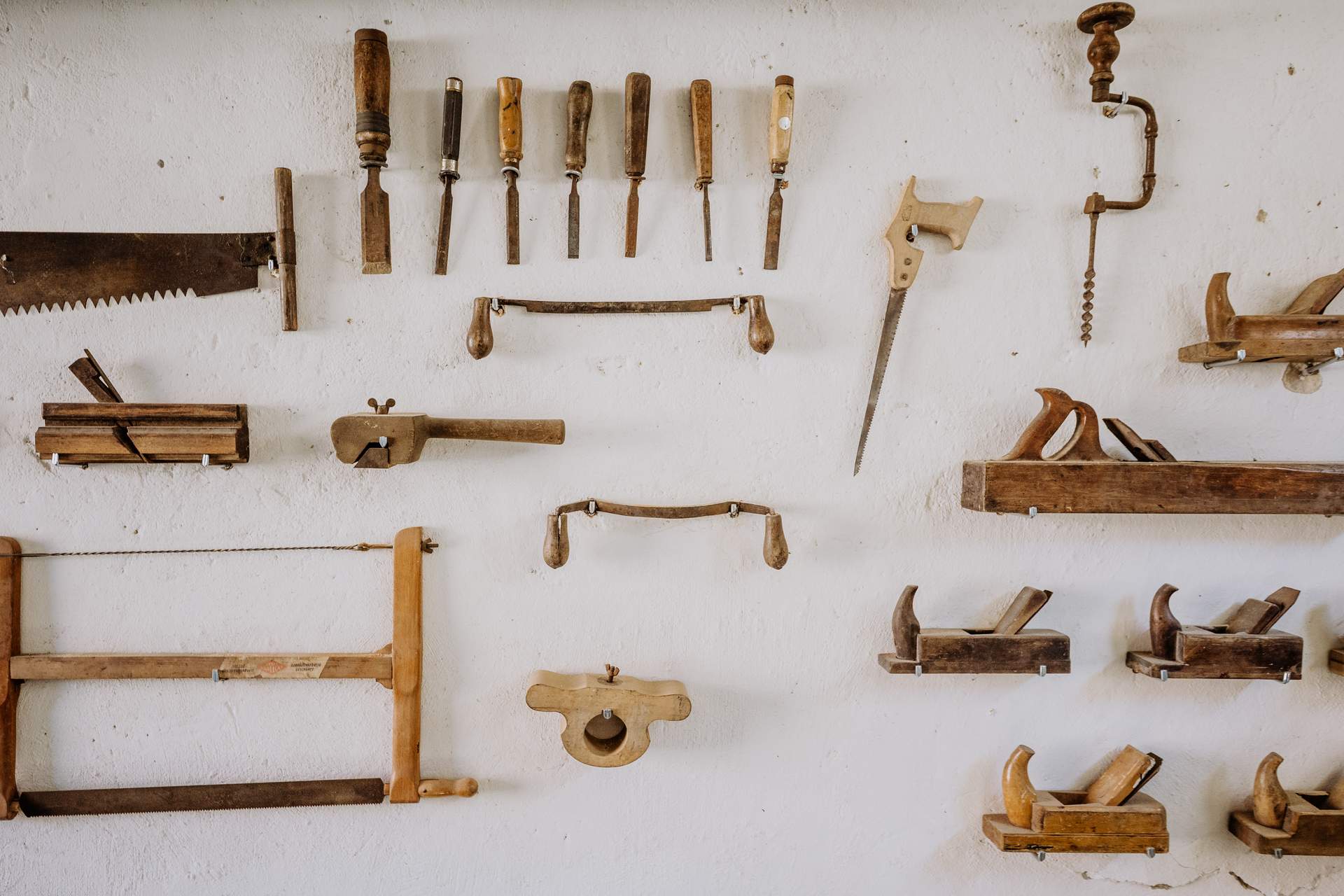Historische Tischlerwerkzeuge wie Holzhobel, Sägen, Feilen und Zwingen an der Holzwand der Durchfahrt