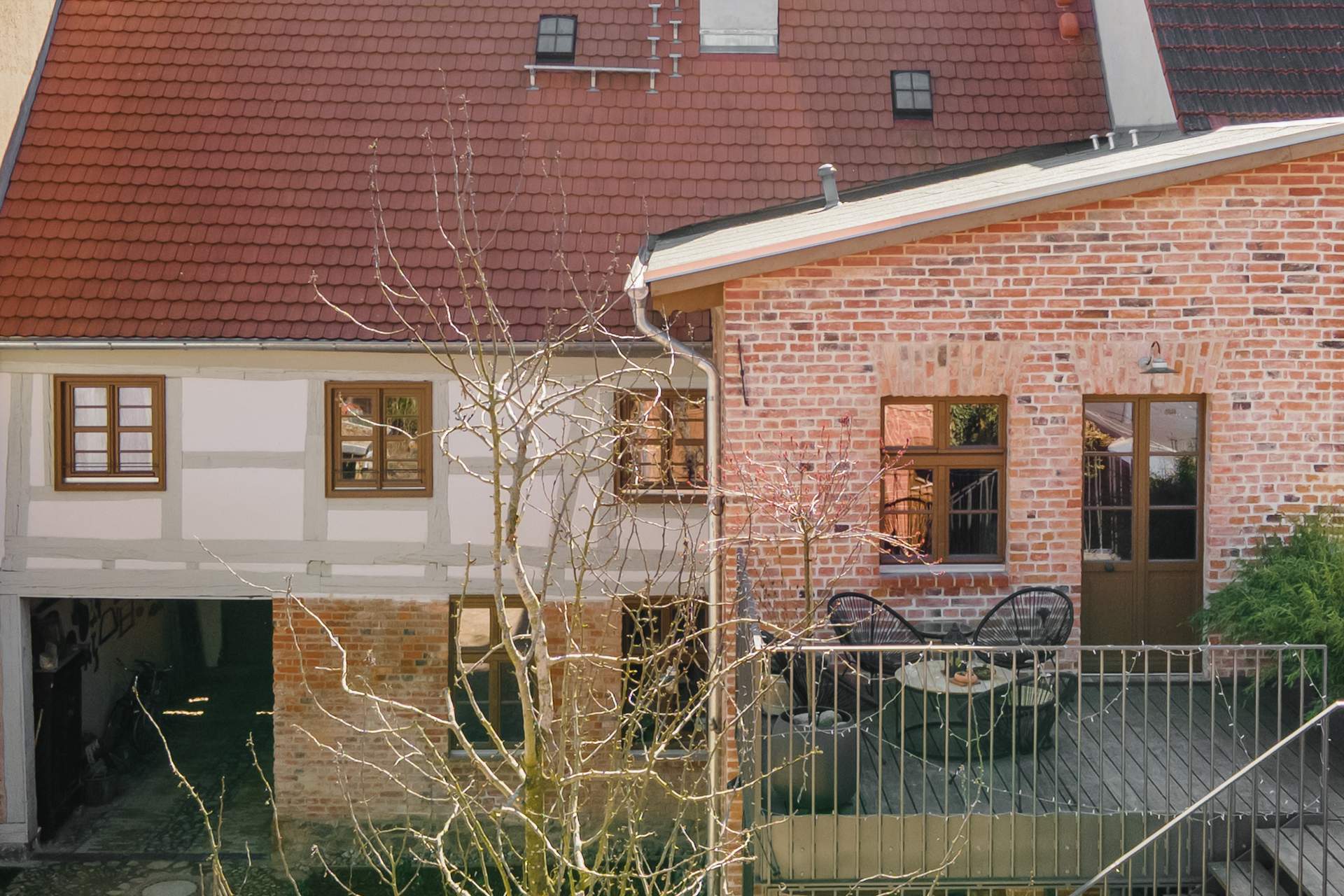 Innenhof und denkmalgeschützte Fachwerkfassade der Alten Tischlerei Gransee mit Ziegelanbau und Sonnenterrasse