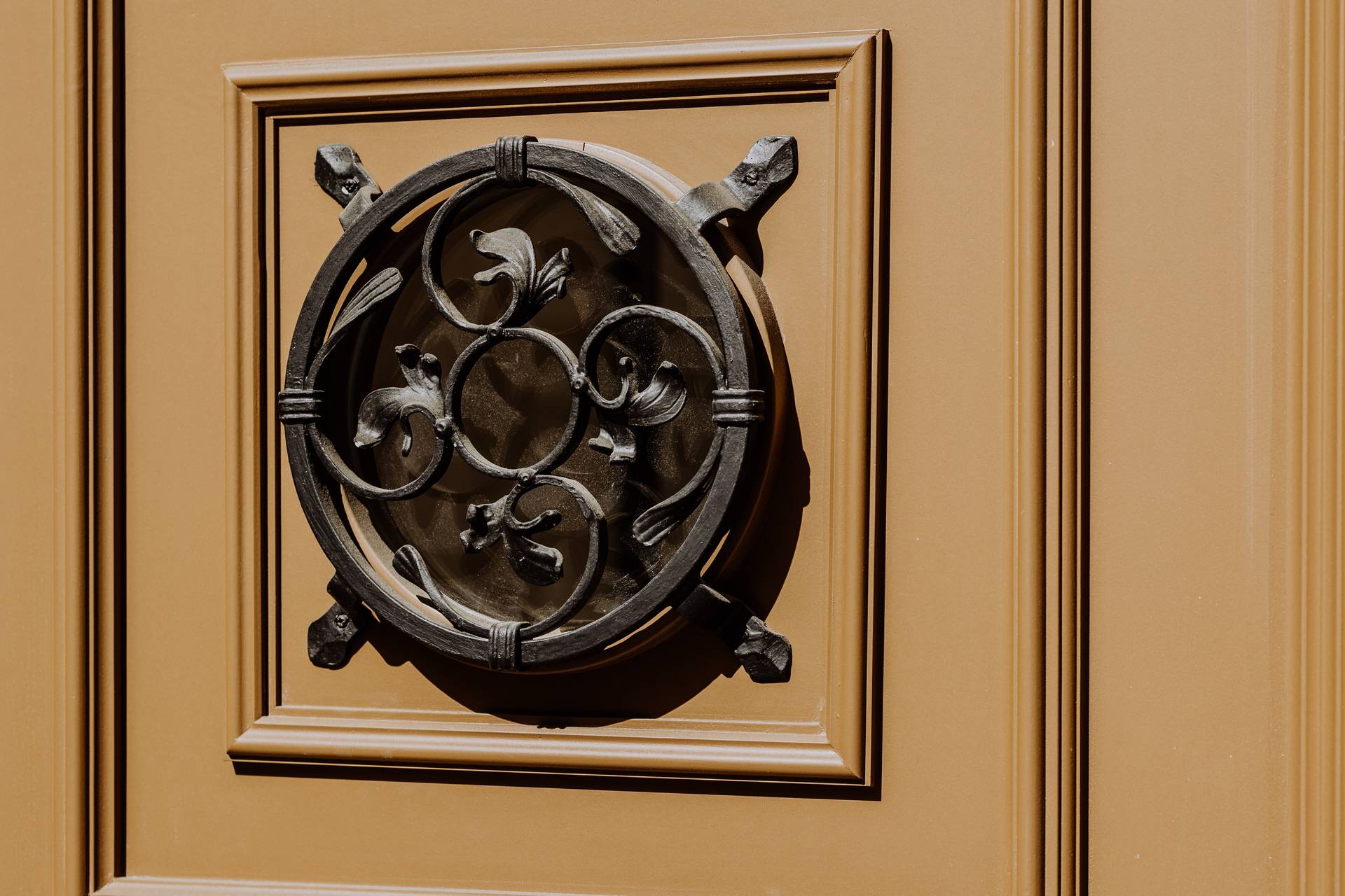 Filigranes schmiedeeisernes Rundfenster mit Ornamenten im historischen Eingangstor